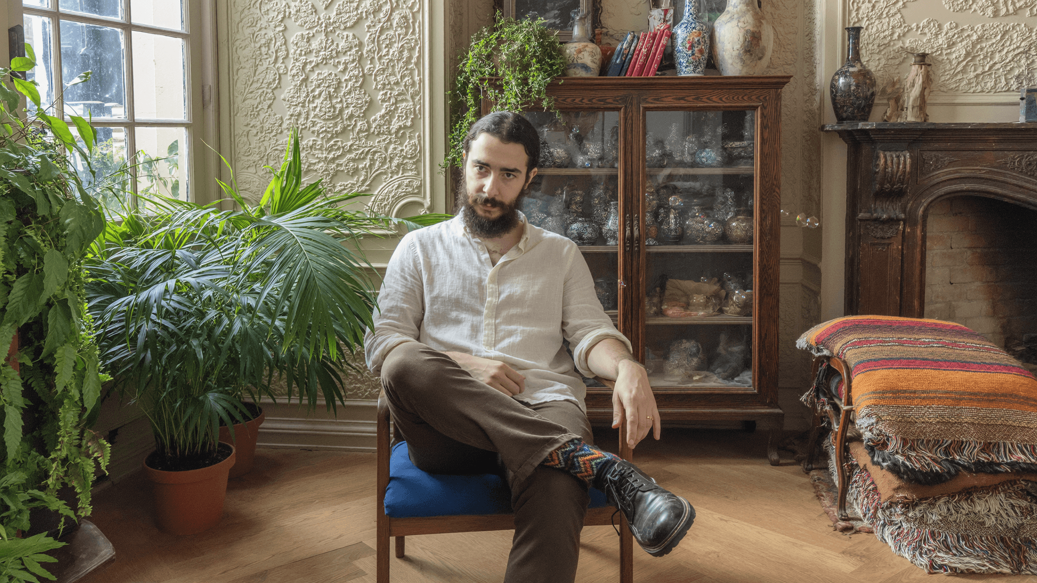 Youssef beside an antique cabinet surrounded by greenery
